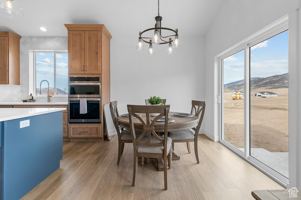 Dining room featuring a mountain view, light wood-style flooring, baseboards, and an inviting chandelier