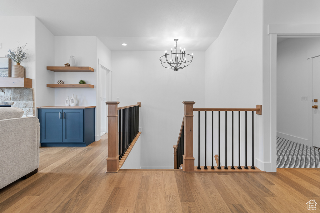 Corridor with light wood-style floors, recessed lighting, a chandelier, and an upstairs landing