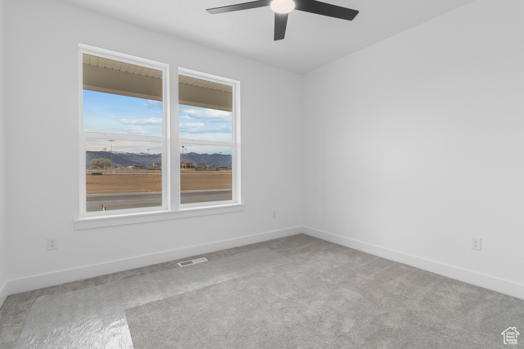 Spare room featuring carpet, visible vents, baseboards, and a ceiling fan