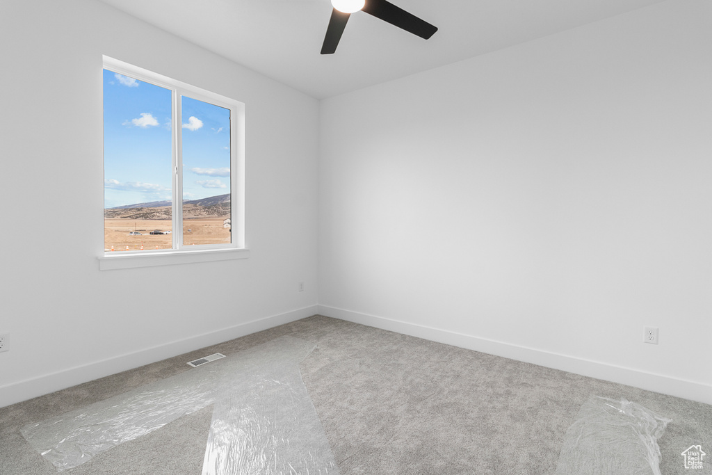 Spare room featuring ceiling fan, carpet, visible vents, and baseboards