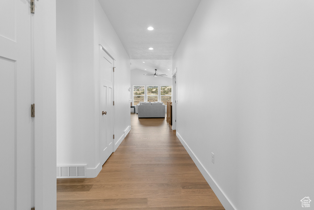 Corridor featuring recessed lighting, visible vents, vaulted ceiling, wood finished floors, and baseboards