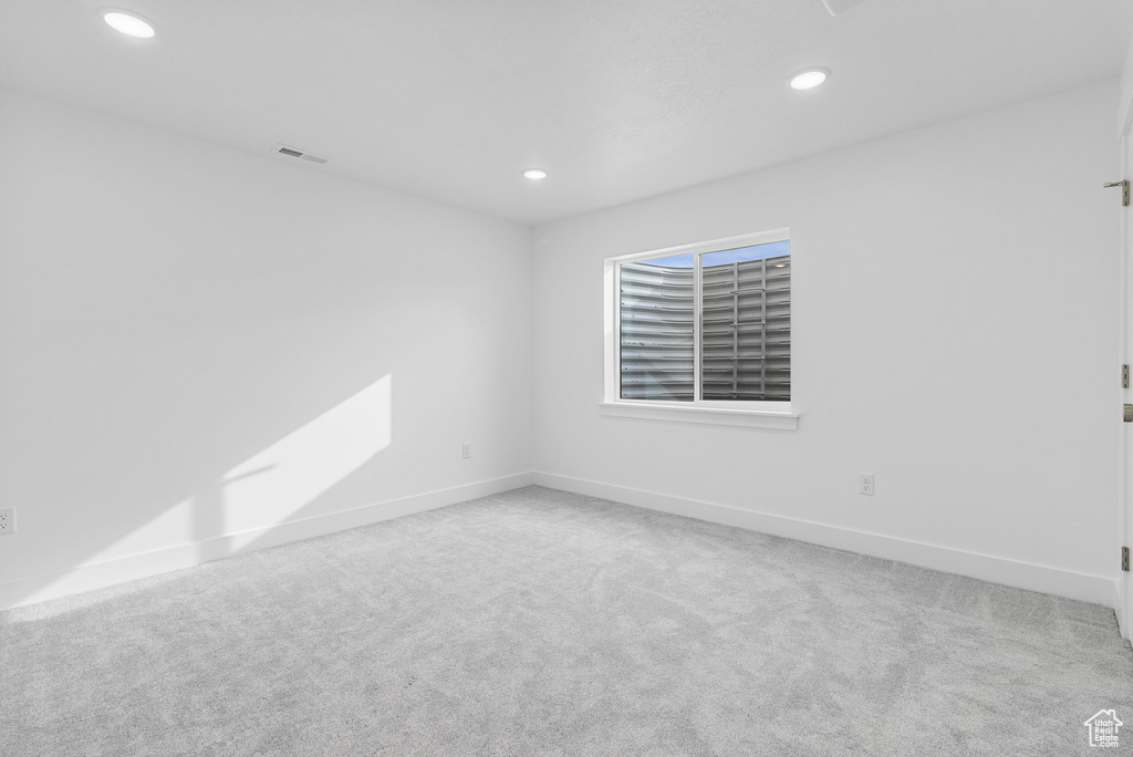 Carpeted spare room with baseboards, visible vents, and recessed lighting