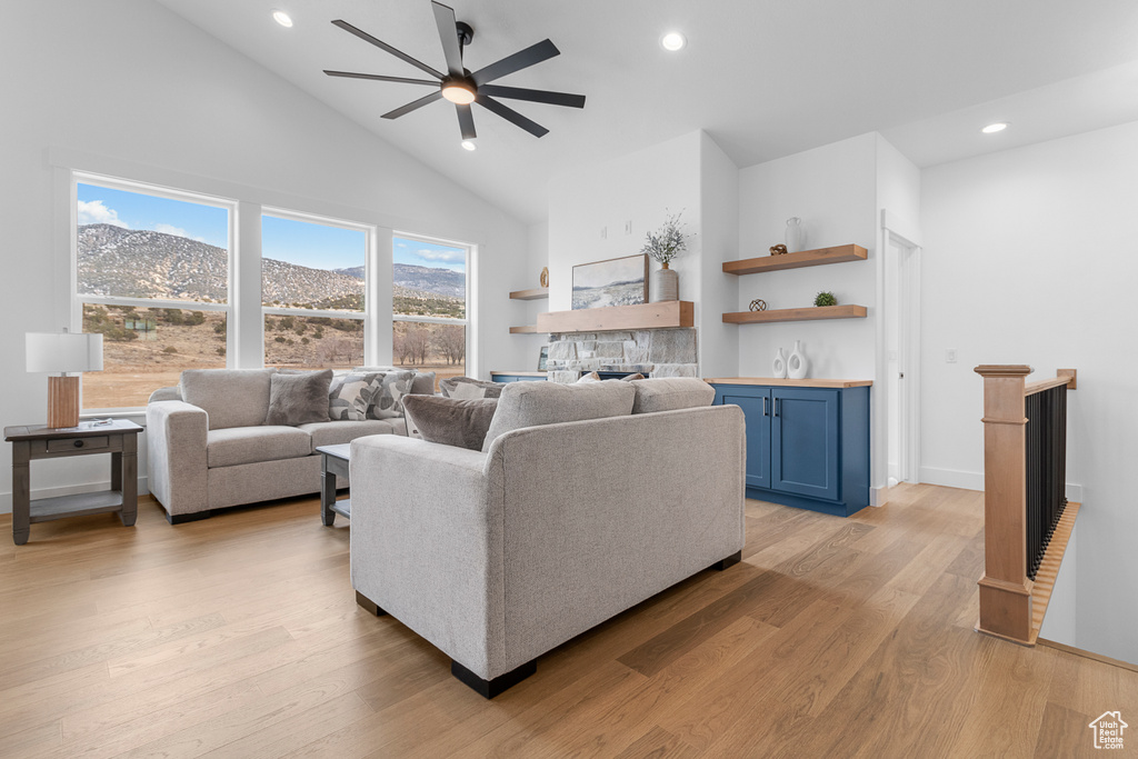 Living area with baseboards, a ceiling fan, light wood-style flooring, a stone fireplace, and recessed lighting