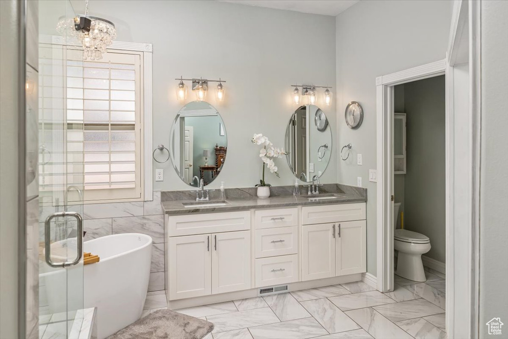 Bathroom featuring tile flooring, tile walls, large vanity, dual sinks, and toilet