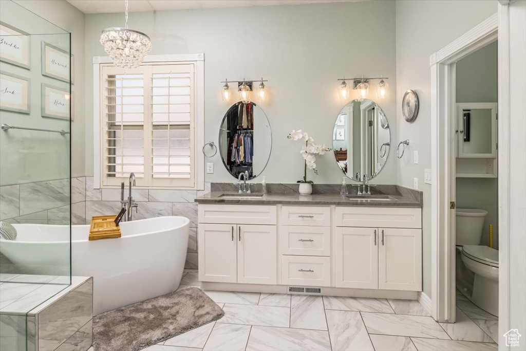 Bathroom featuring a bathing tub, toilet, tile flooring, dual vanity, and a chandelier