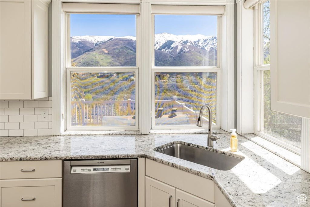 Kitchen with a mountain view, dishwasher, white cabinets, and sink
