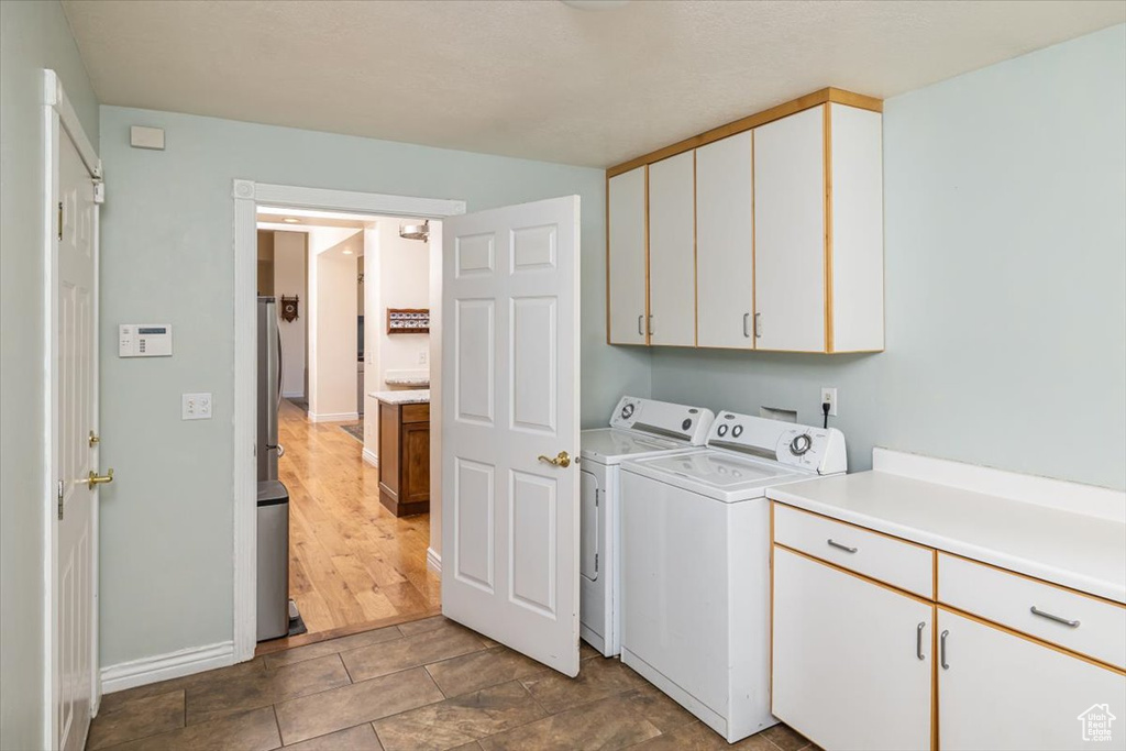 Laundry area featuring cabinets, tile floors, and washing machine and clothes dryer