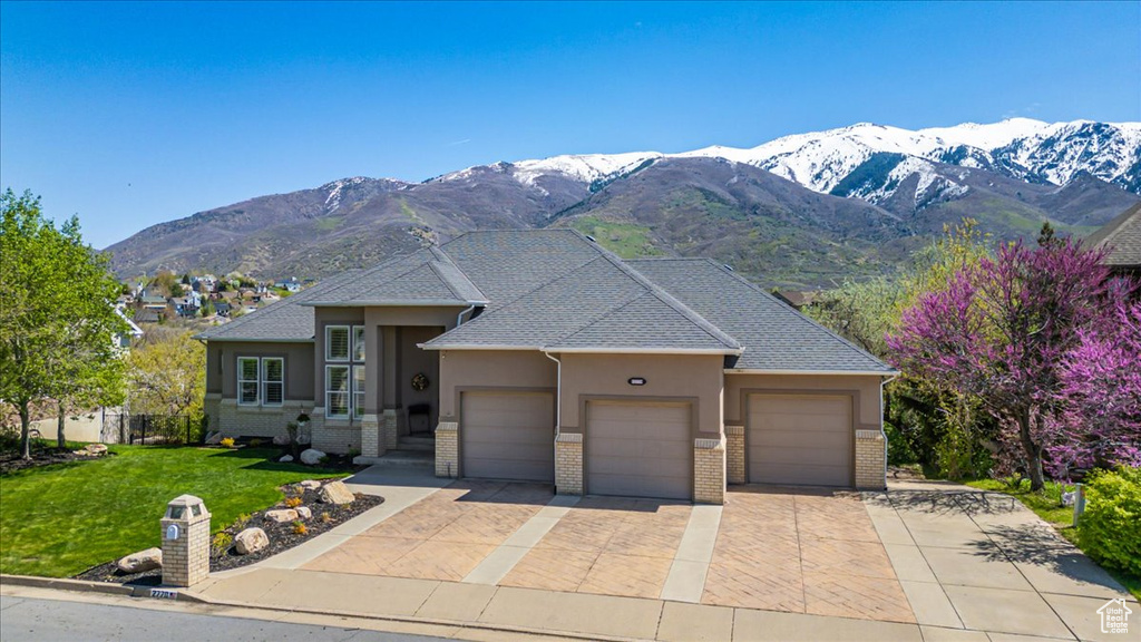 View of front of home with a mountain view, a front lawn, and a garage