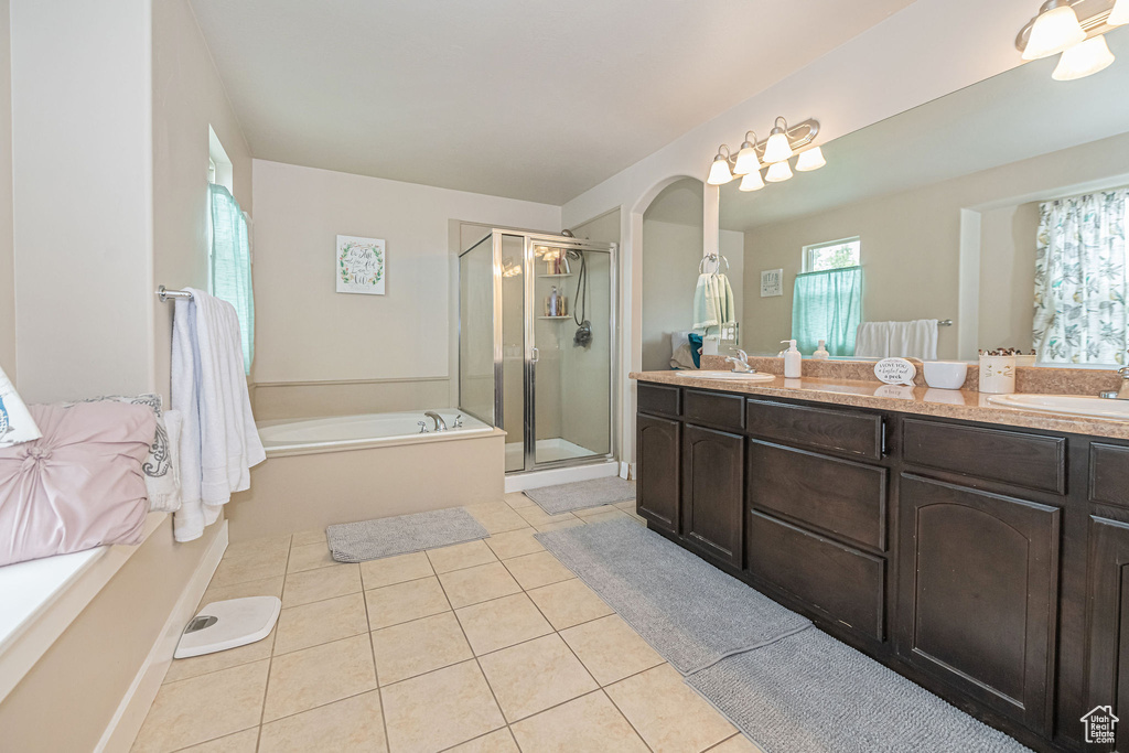 Bathroom with plenty of natural light, independent shower and bath, dual vanity, and tile flooring