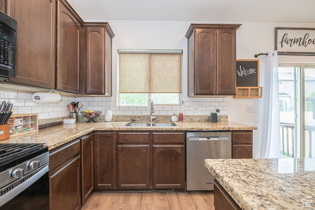 Kitchen featuring backsplash, appliances with stainless steel finishes, sink, and light wood-type flooring
