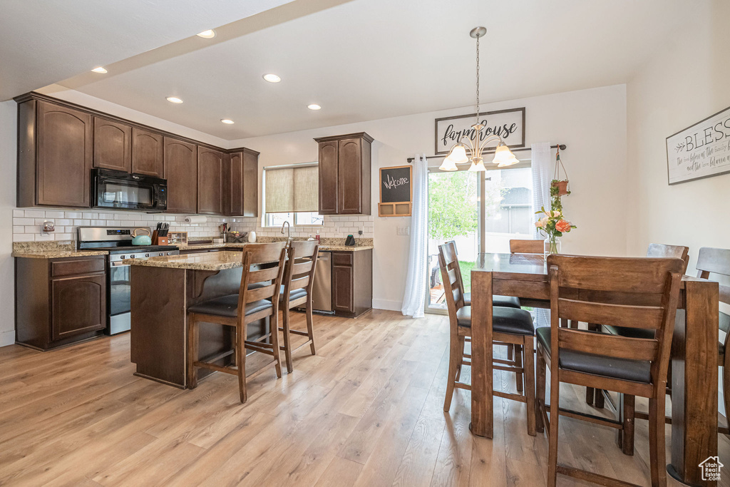 Kitchen featuring light hardwood / wood-style flooring, a center island, stainless steel appliances, and light stone countertops