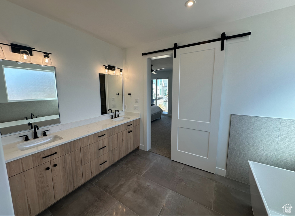 Bathroom featuring a washtub, dual bowl vanity, and tile flooring