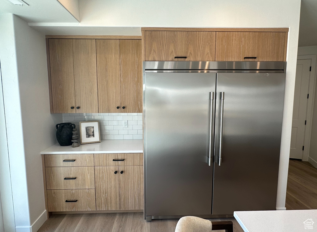 Kitchen featuring backsplash, built in refrigerator, and light hardwood / wood-style flooring