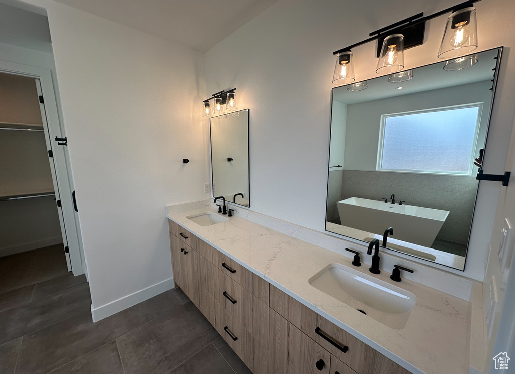 Bathroom featuring a bathtub, double vanity, and tile flooring