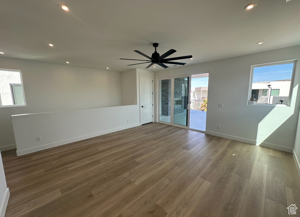 Unfurnished room with ceiling fan, dark hardwood / wood-style floors, and plenty of natural light