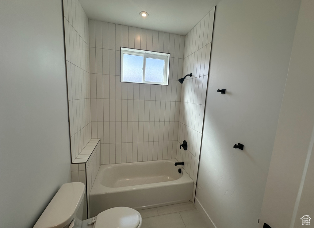 Bathroom with tile floors, toilet, and tiled shower / bath