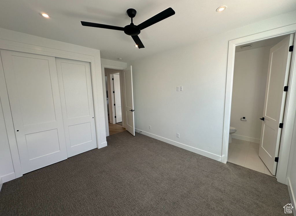 Unfurnished bedroom featuring a closet, ceiling fan, dark carpet, and ensuite bathroom