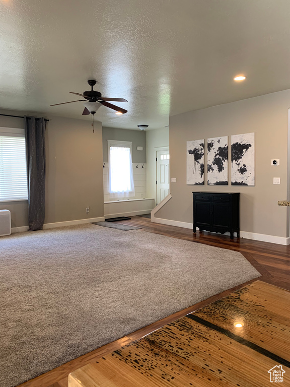 Unfurnished living room with a textured ceiling, carpet floors, and ceiling fan