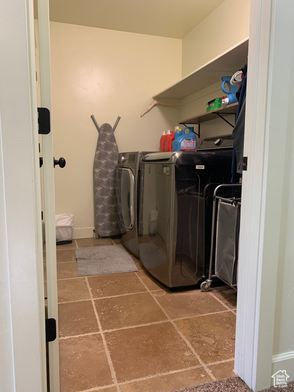 Clothes washing area featuring tile floors and separate washer and dryer