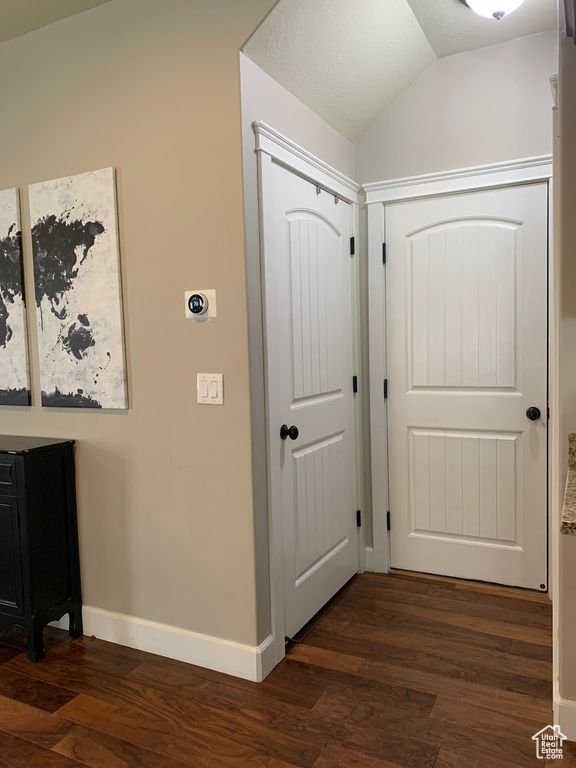 Corridor with dark hardwood / wood-style flooring and lofted ceiling