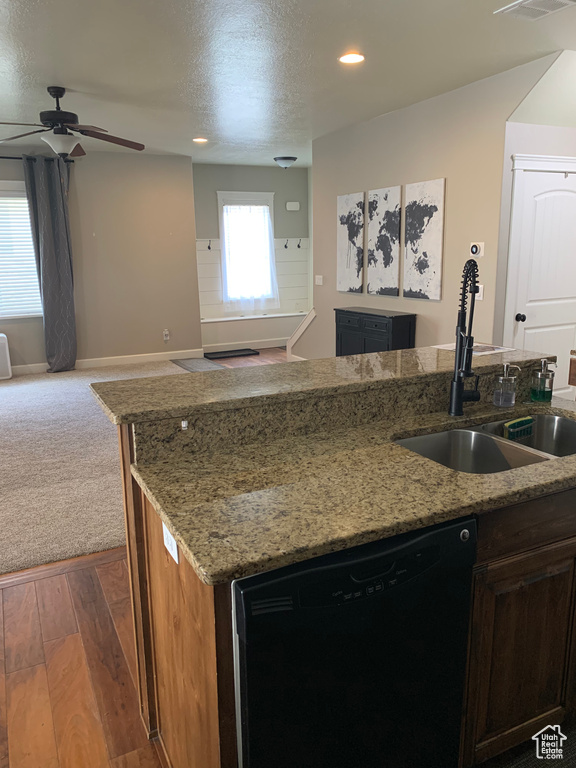 Kitchen featuring light stone countertops, ceiling fan, dishwasher, carpet flooring, and sink