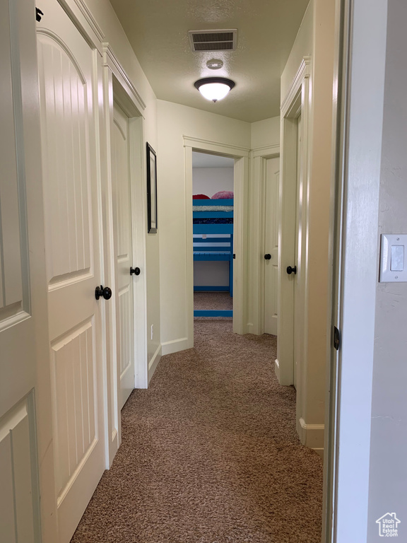 Hallway featuring dark carpet
