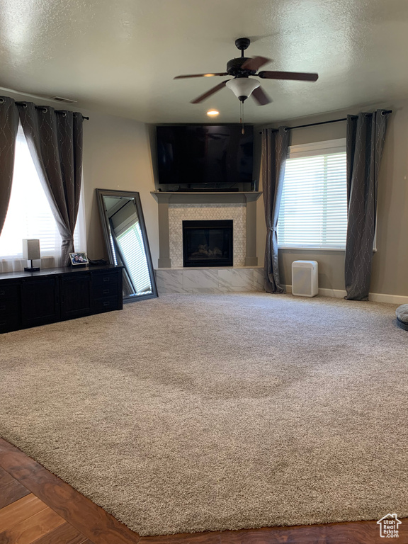 Unfurnished living room featuring a textured ceiling, ceiling fan, and carpet flooring