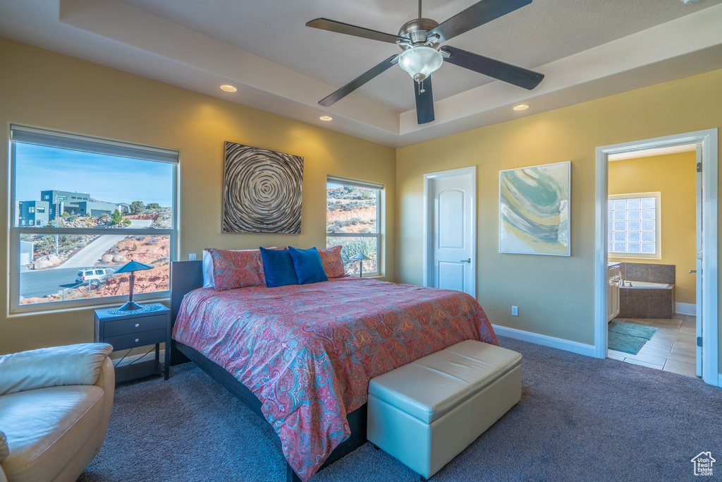 Bedroom featuring a tray ceiling, ensuite bath, ceiling fan, and carpet