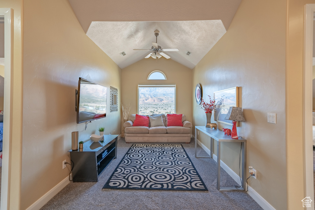 Carpeted living room with ceiling fan and vaulted ceiling