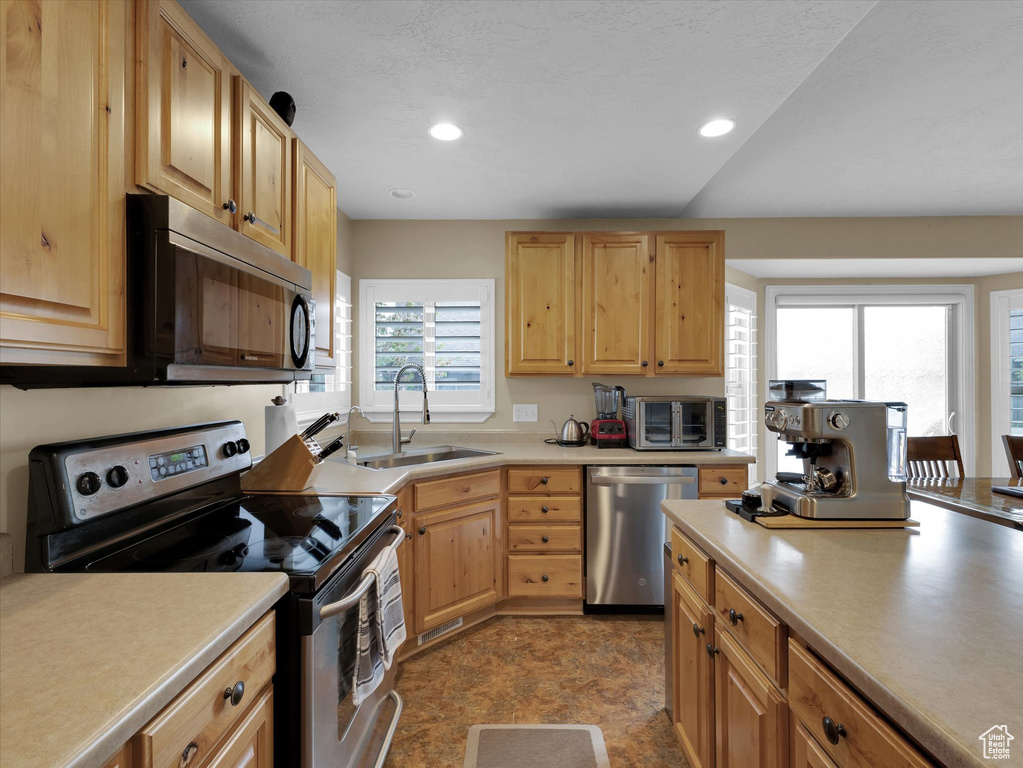 Kitchen with sink, plenty of natural light, light tile floors, and stainless steel appliances