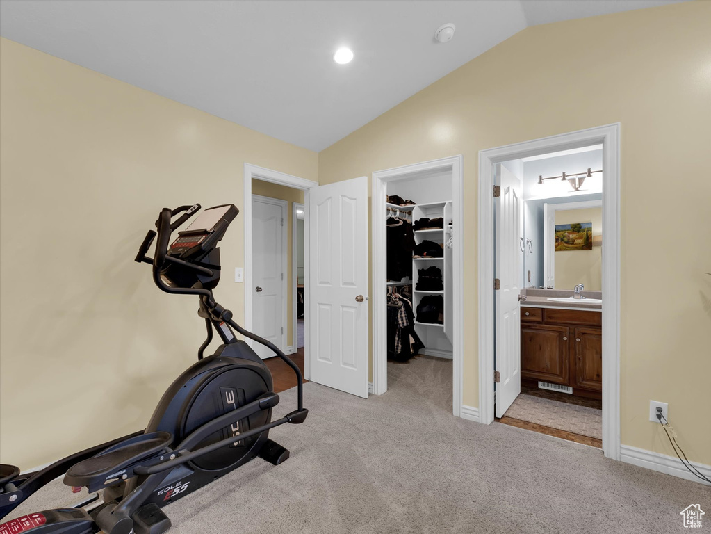 Exercise room with light colored carpet, sink, and vaulted ceiling