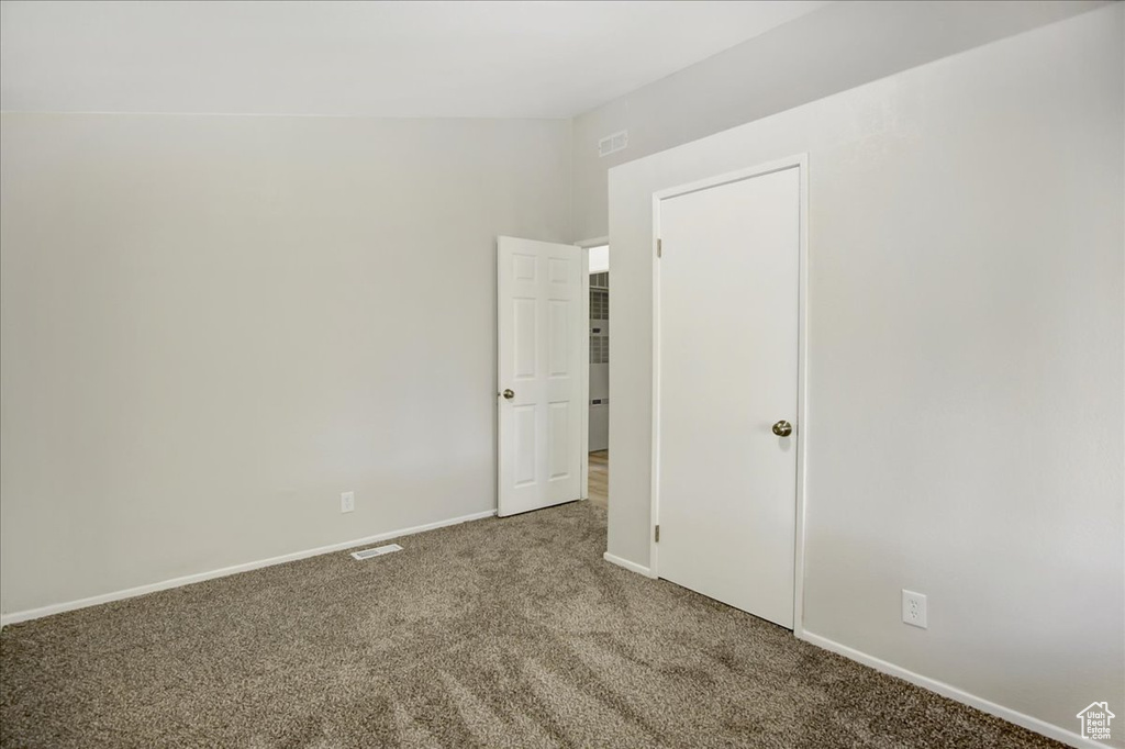 Unfurnished bedroom with carpet and vaulted ceiling