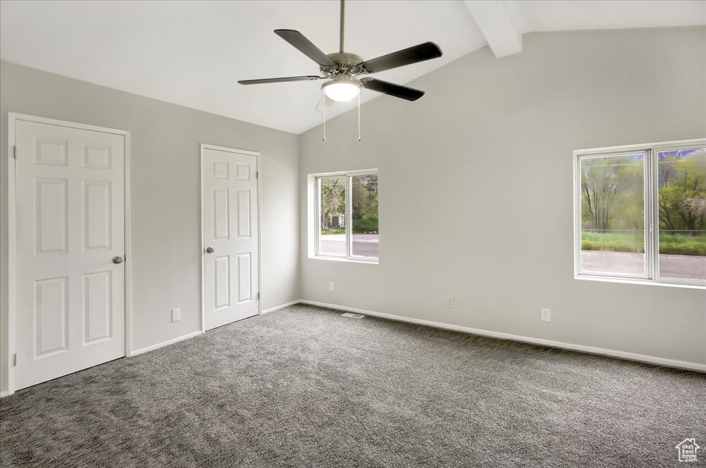 Unfurnished bedroom with ceiling fan, beam ceiling, two closets, and carpet floors