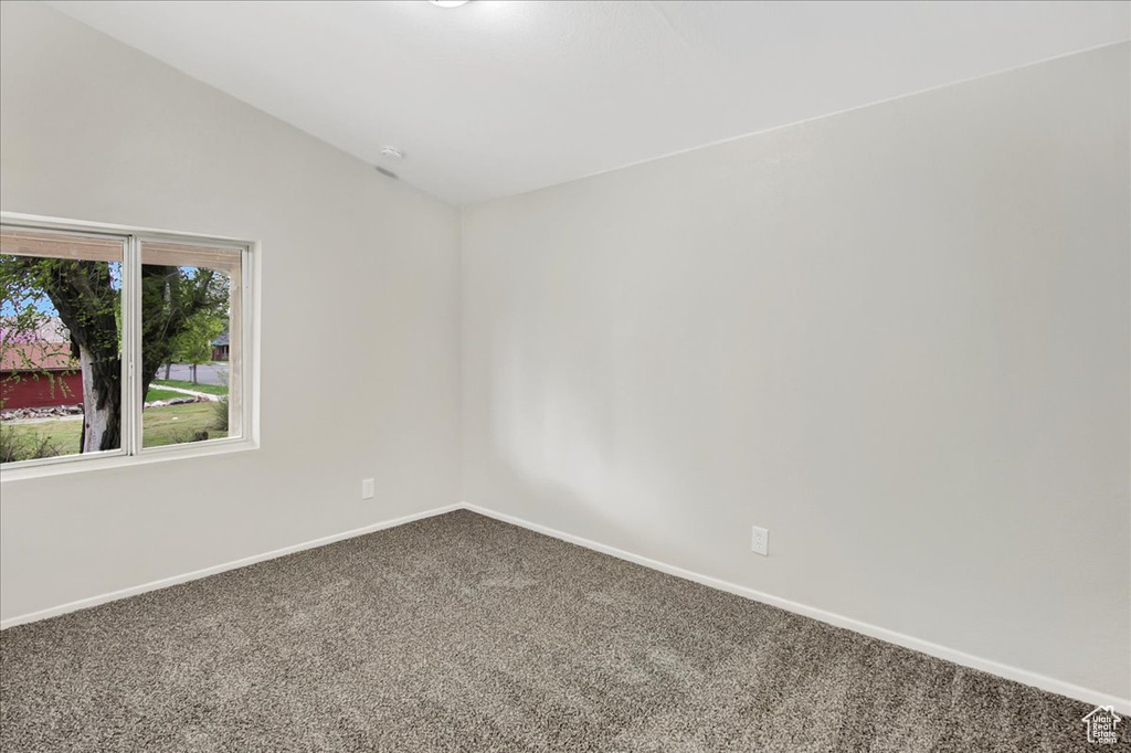Empty room featuring vaulted ceiling and carpet flooring