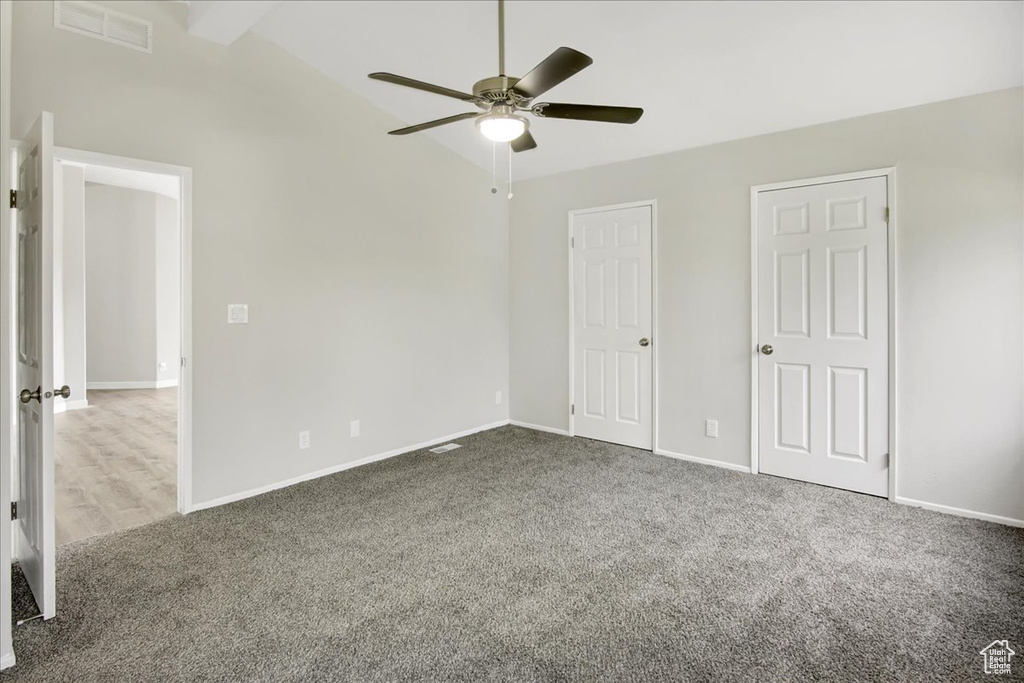 Spare room featuring vaulted ceiling, ceiling fan, and carpet flooring