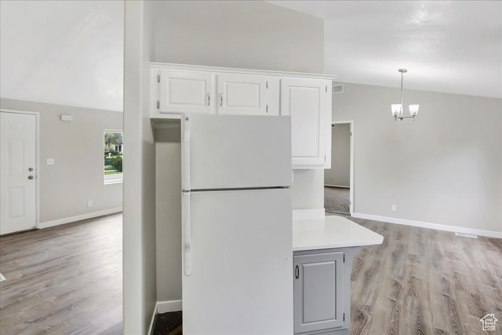 Kitchen featuring light hardwood / wood-style flooring, white fridge, white cabinetry, and a notable chandelier