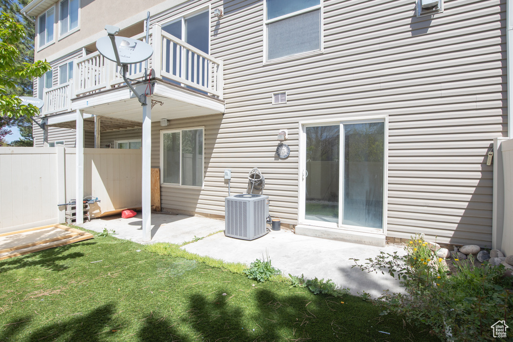 Rear view of property featuring central AC, a yard, a balcony, and a patio
