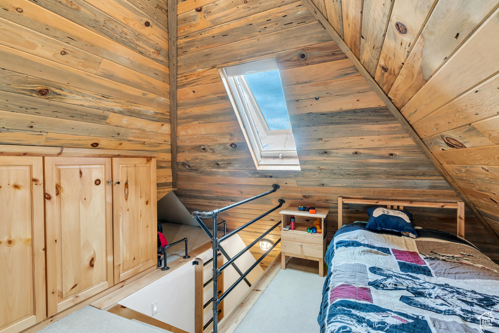 Bedroom featuring wooden ceiling, wood walls, and lofted ceiling with skylight