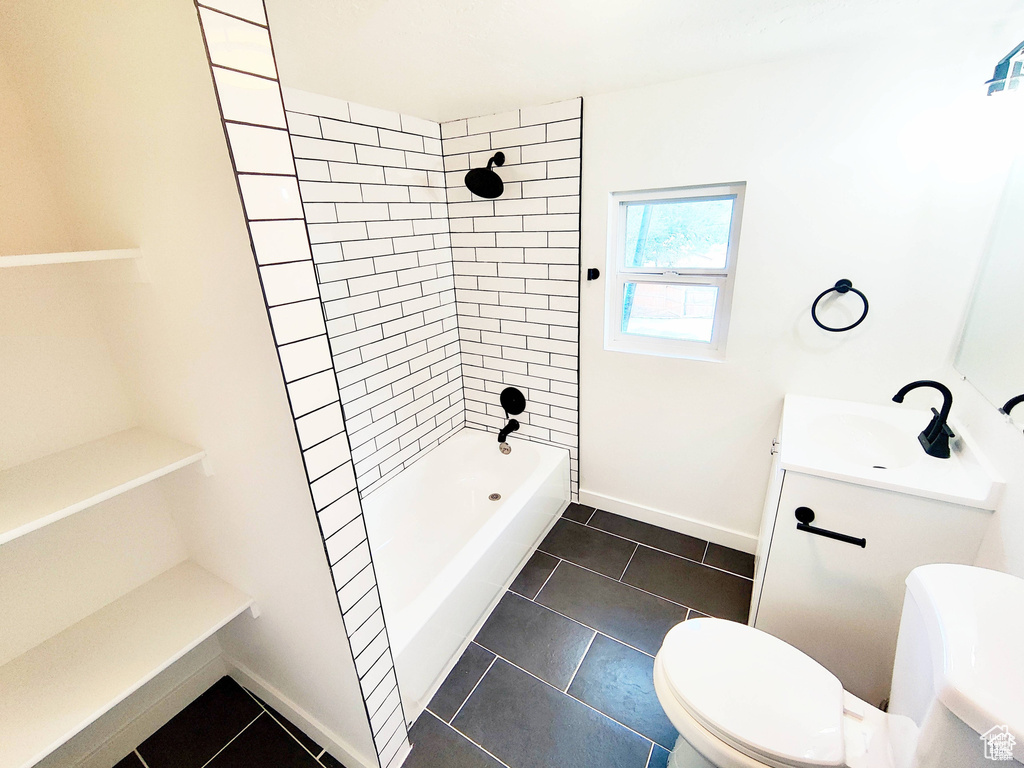 Full bathroom featuring tile floors, vanity, tiled shower / bath combo, and toilet