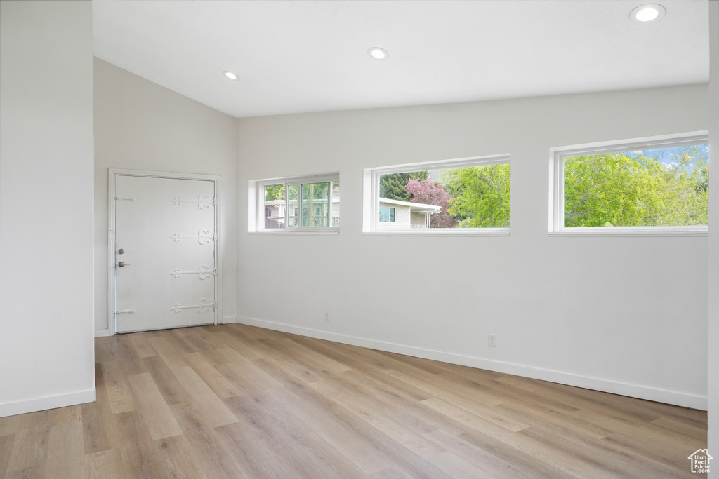 Empty room featuring lofted ceiling and light hardwood / wood-style flooring