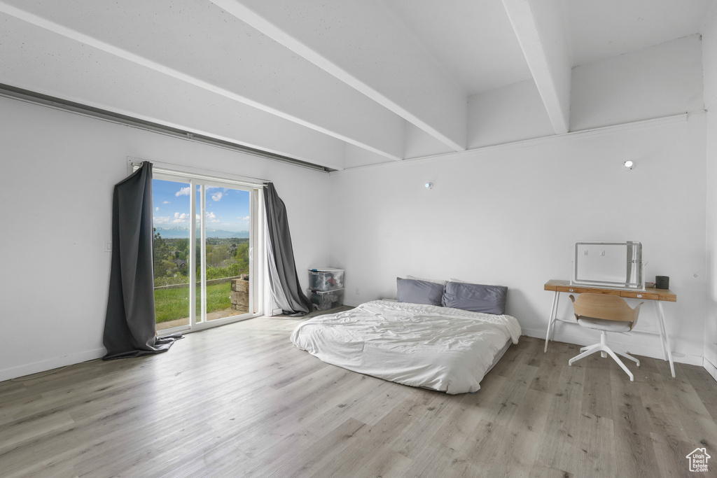 Bedroom with wood-type flooring and beam ceiling