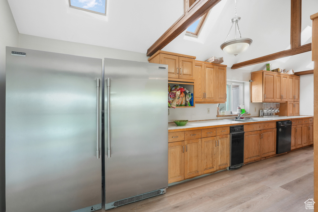 Kitchen with high end fridge, decorative light fixtures, light hardwood / wood-style flooring, dishwasher, and sink