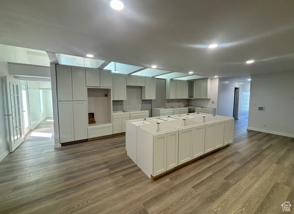 Kitchen featuring hardwood / wood-style floors, a center island, and white cabinetry