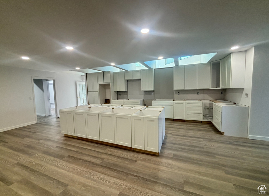 Kitchen with a center island with sink, white cabinetry, and hardwood / wood-style floors