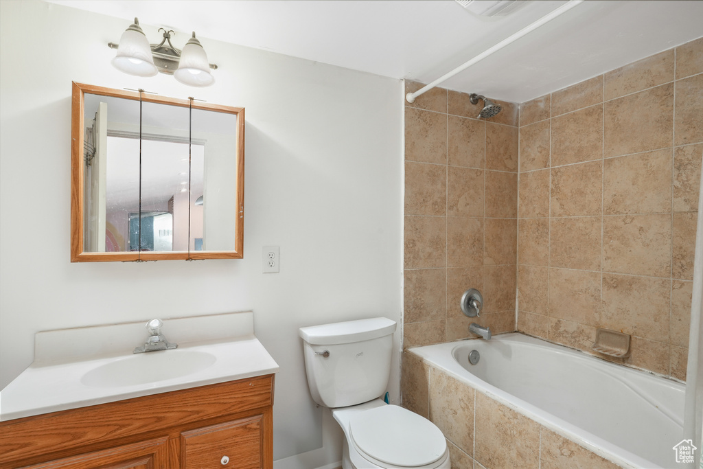 Full bathroom featuring vanity with extensive cabinet space, tiled shower / bath combo, and toilet