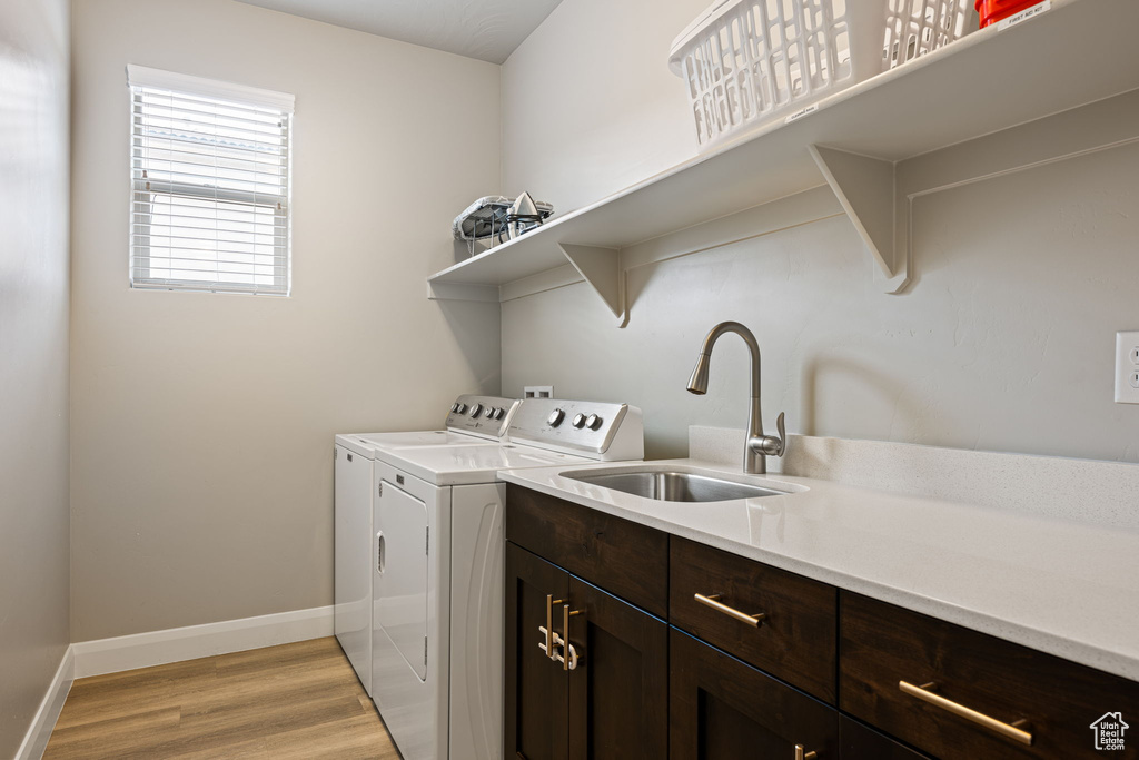 Laundry room with sink, light hardwood / wood-style flooring, independent washer and dryer, and cabinets