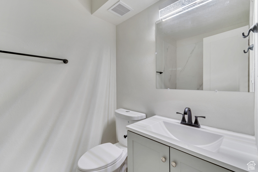 Bathroom with vanity with extensive cabinet space and toilet