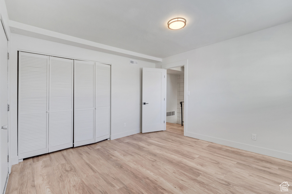 Unfurnished bedroom with a closet and light hardwood / wood-style flooring