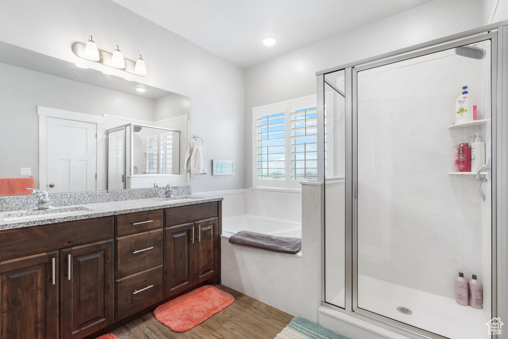 Bathroom featuring dual sinks, oversized vanity, hardwood / wood-style flooring, and separate shower and tub