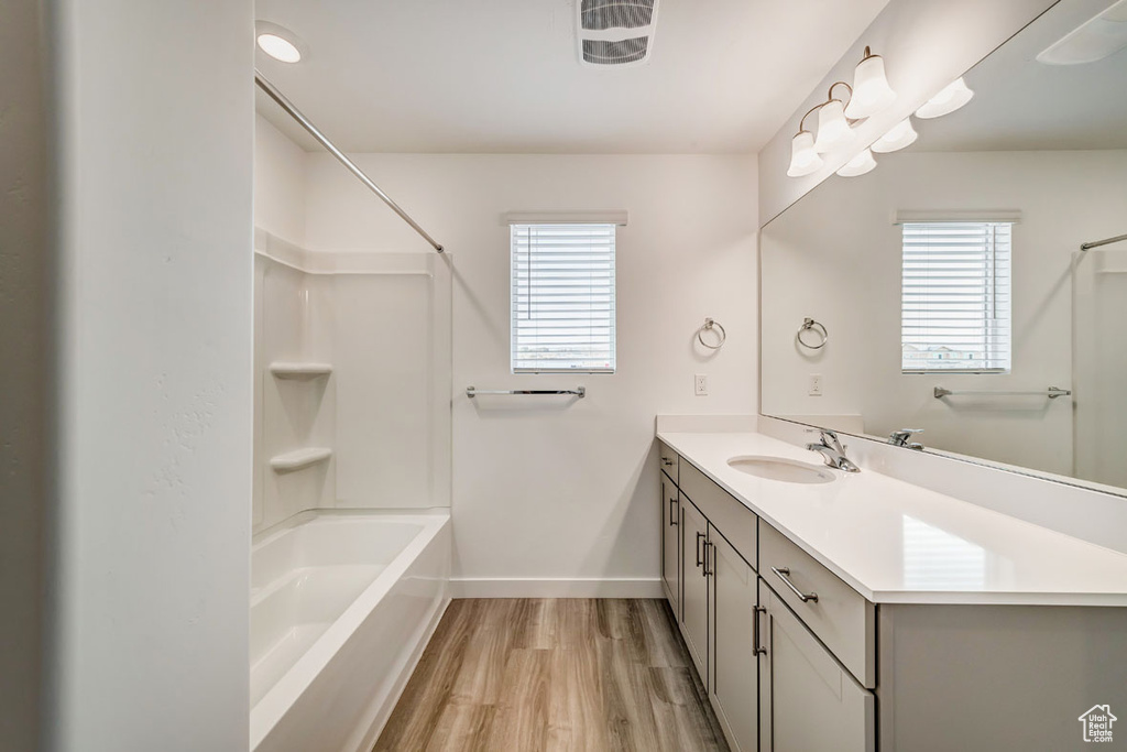 Bathroom with hardwood / wood-style flooring, plenty of natural light, oversized vanity, and tub / shower combination